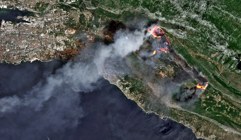 Imagen satelital de un incendio forestal costero, con varios frentes activos y densas columnas de humo.